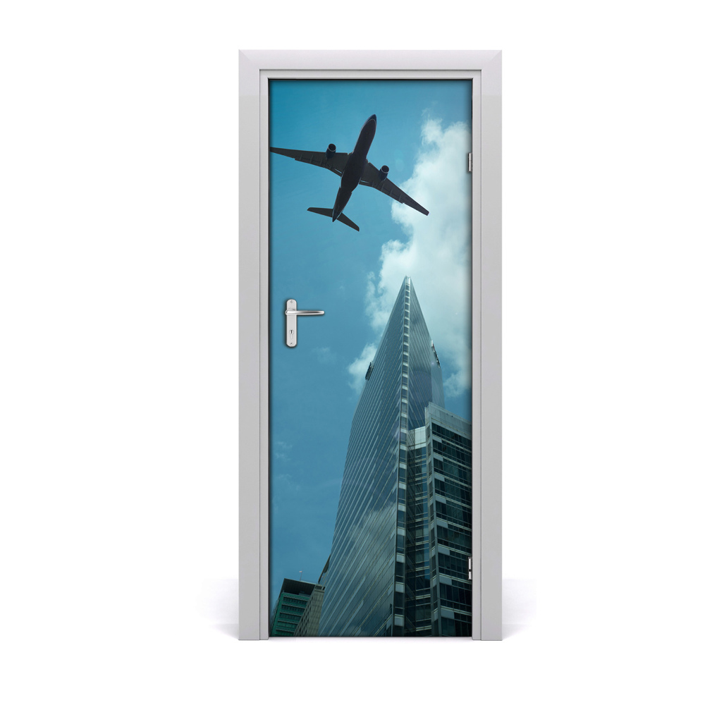 Fototapeta samoprzylepna drzwi Samolot na niebie nad miastem