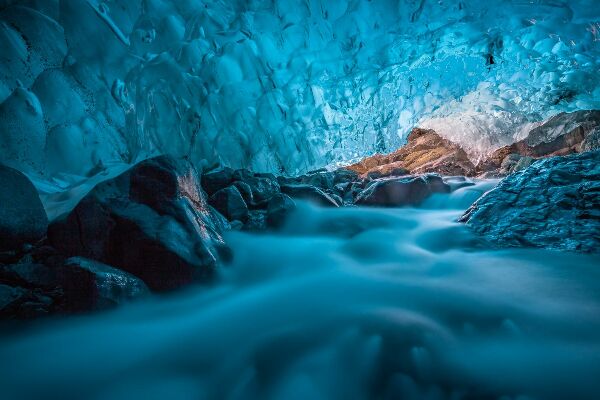 Fototapeta Grota di ghiaccio azzurro con ruscello sottostante islanda europa