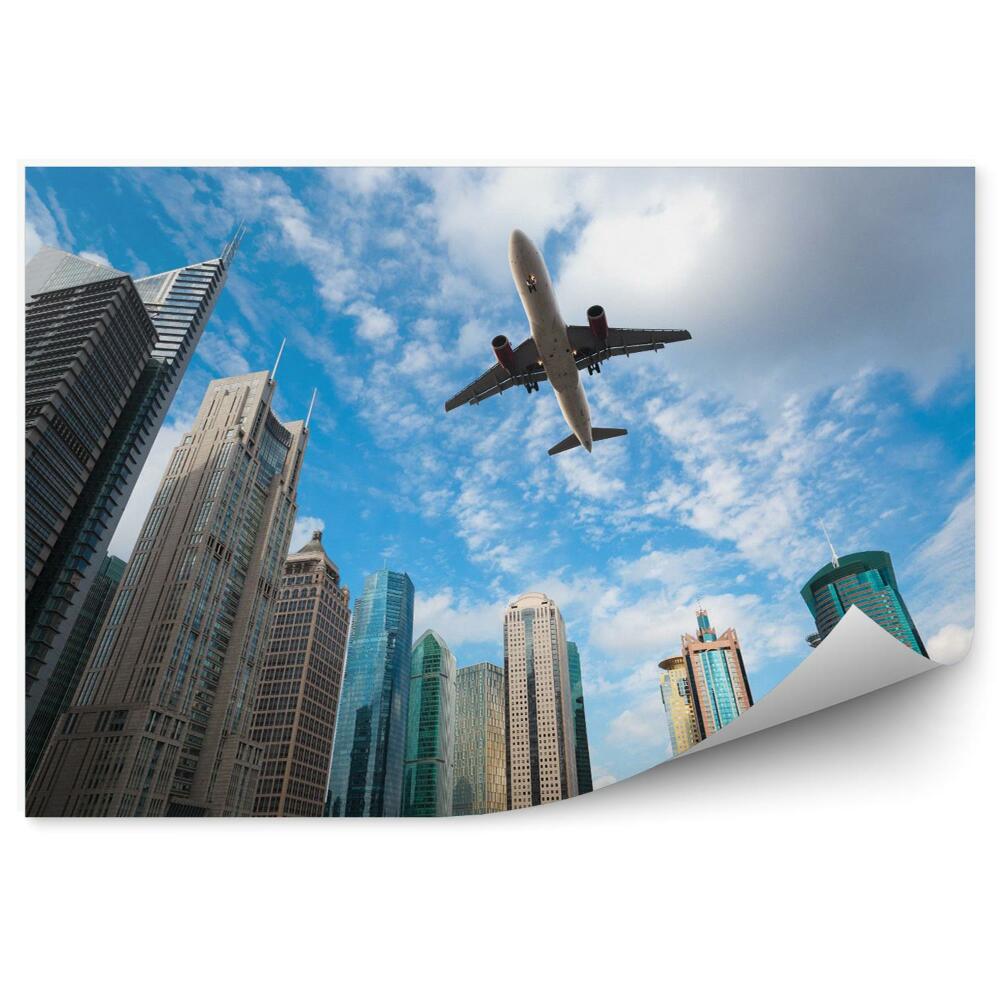 Fototapeta Samolot na tle błękitnego nieba i nowoczesnych budynków